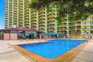 Piscina rodeada por um edifício com várias andares e varandas.