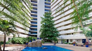 Un hotel a più piani con un cortile centrale, una piscina e vegetazione rigogliosa.