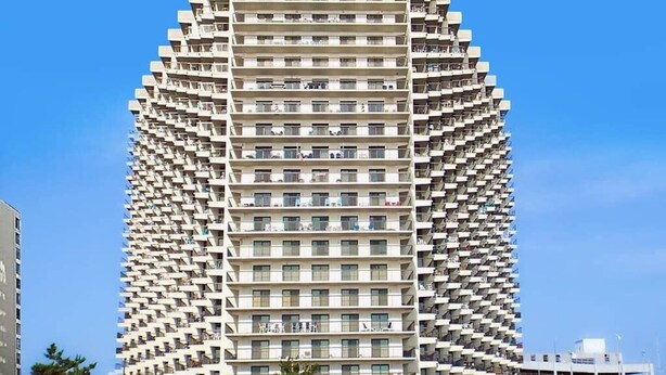Un edificio de gran altura con un diseño arquitectónico único, que cuenta con varios balcones y una fachada uniforme.