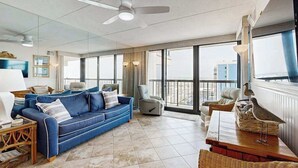 Un salón amplio con un sofá azul, una mesa de comedor y un balcón con vistas.