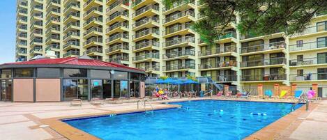 A swimming pool surrounded by a building with multiple balconies.