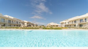 Un resort con piscina, edificios modernos y cielo despejado.