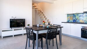 Una cocina moderna con armarios blancos, un salpicadero de azulejos y una zona de comedor con mesa y sillas.
