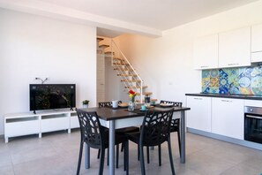 A modern kitchen with white cabinets, a tiled backsplash, and a dining area with a table and chairs. - Charming two-level apartment, accommodating up to 5 people, located within the renowned Borgo 84 residence, featuring two swimming pools and a bike path. The property is located just 3 km from the center of Marzamemi, one of the most fascinating seaside  (Pachino)