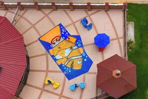 Ein Terrassenbereich mit Fliesenboden, einem großen Sonnenschirm und Gartenmöbeln.
