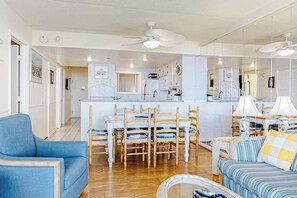 Amplia sala de estar con una mesa de comedor, sillas, sofás y una cocina al fondo.