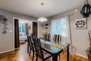 A dining area with a wooden table, chairs, a hanging light fixture, and a decorative wall piece. - Seafarer 7 (Ocean Pines)