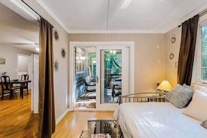A bedroom with a bed, a nightstand, a lamp, a window, and a sliding glass door leading to a balcony. - Seafarer 7 (Ocean Pines)