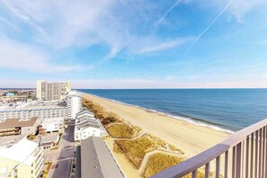 A coastal hotel with a beach view, a parking lot, and a row of buildings along the shore. - Sea Terrace 1401 (Ocean City)
