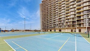 Ein Tennisplatz im Freien neben einem Hochhaus mit mehreren Balkonen.