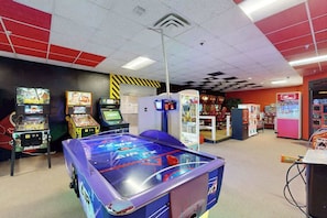 Une salle avec une table de billard, des jeux d’arcade et un distributeur automatique.