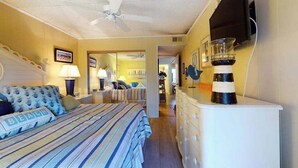 Ein Hotelzimmer mit Bett, Kommode, Deckenventilator, Fernseher und Spiegel.