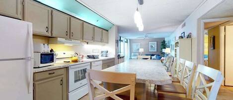 A modern kitchen with a dining area, white cabinets, and a large island.