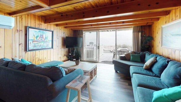 Ein Holzhütten-Innenraum mit einem Wohnbereich, der Sofas, einen Couchtisch und einen Fernseher zeigt.