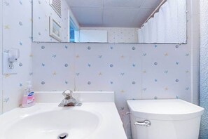 A bathroom with a sink, toilet, and a mirror above the sink. - Sea Place 108 (Ocean City)