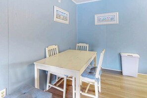 A room with a white table and chairs, a trash bin, and two framed pictures on the wall. - Sea Place 108 (Ocean City)