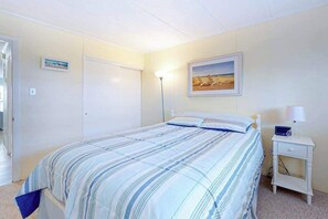 Ein Schlafzimmer mit Bett, Nachttisch, Lampe und einem gerahmten Bild an der Wand.