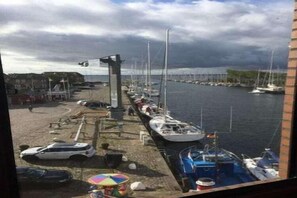 Ein Yachthafen mit vertäuten Booten, einem Fußweg und Blick auf das Wasser.