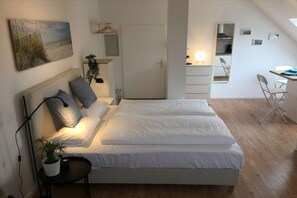 Ein Schlafzimmer mit Bett, Nachttisch, Lampe und einer Pflanze.