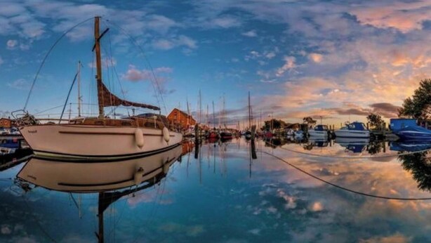Una marina con barche ormeggiate, acque calme e cielo sereno.