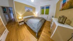 Una camera da letto con un letto, un comodino, una lampada, una finestra e un'opera d'arte appesa al muro.