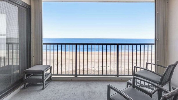 Un balcone con vista sulla spiaggia, una sedia e un tavolino.