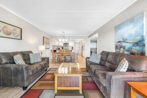 Ein modernes Wohnzimmer mit zwei Ledersofas, einem Holztisch und einem Essbereich mit Tisch und Stühlen.