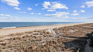 Ein Strand mit blauem Himmel und einem Sandweg, der zum Wasser führt.