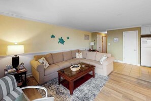 A living room with a beige sofa, a glass coffee table, and a striped armchair. - Newly updated condo - less than a block to the beach (Ocean City)