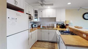 A kitchen with white cabinets, a microwave, a toaster, a sink, and a clock on the wall. - Newly updated condo - less than a block to the beach (Ocean City)