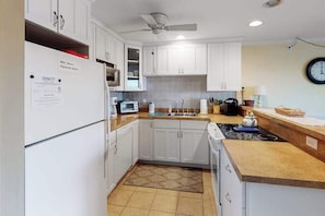 A kitchen with white cabinets, a microwave, a toaster, a sink, and a clock on the wall. - Newly updated condo - less than a block to the beach (Ocean City)