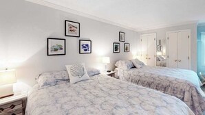A bedroom with two beds, a nightstand, a dresser, and a wall with framed pictures. - Newly updated condo - less than a block to the beach (Ocean City)