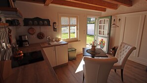 Una cocina con armarios de madera, un fregadero y una zona de comedor con una mesa y una silla.