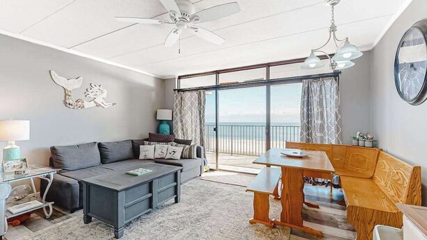 A modern living room with a sofa, coffee table, wooden bench, and a dining table. - Oceanfront Condo w/ Great Beach View, Balcony, AC, W/D & Shared Pool/Tennis (Ocean City)