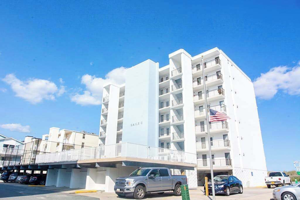 A multi-story building with balconies, a parking area, and an American flag.