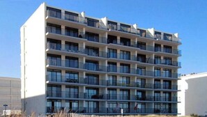 A multi-story building with balconies, large windows, and a flat facade. - Oceanfront Condo w/ Great Beach View, Balcony, AC, W/D & Shared Pool/Tennis (Ocean City)