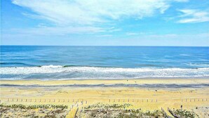 Une plage avec un rivage sablonneux, un ciel dégagé et l’océan.