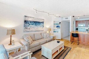 A modern living room with a sofa, coffee table, and a painting on the wall. - Newly Updated, Oceanfront Condo with New AC, WiFi, Balcony & Shared Pool (Ocean City)