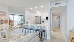 Eine moderne Küche mit weißen Schränken, einem Edelstahl-Kühlschrank und einer Bar mit Barhocker.