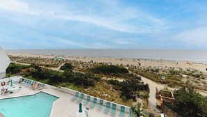 Ein Poolbereich mit Liegestühlen und Blick auf den Strand.