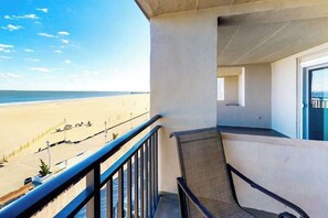 A balcony with a view of the beach, a chair, and a door. - Polynesian 503 (Ocean City)