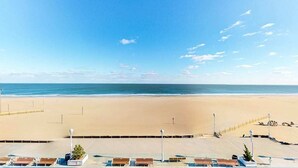 Uitzicht op een strand met heldere lucht, zandstrand en een rij ligbedden.