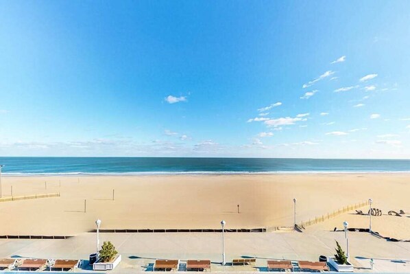 A beach view with a clear sky, a sandy beach, and a row of sun loungers. - Polynesian 503 (Ocean City)