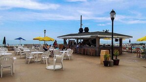 Un área de estar al aire libre con mesas, sillas, un bar y sombrillas.