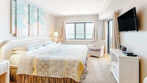 Un dormitorio con cama, una silla, un televisor y una ventana con vistas.