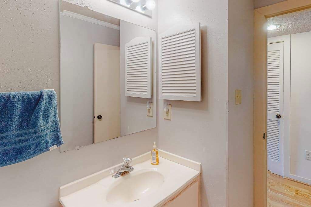 A bathroom with a sink, mirror, towel, and white wall-mounted towel racks.