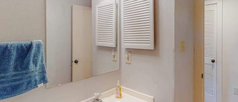 A bathroom with a sink, mirror, towel, and white wall-mounted towel racks.