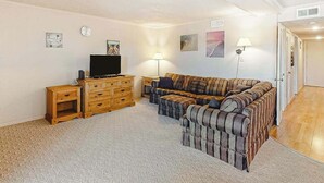 A living room with a sofa, a TV, wooden furniture, and wall art. - Our Place At The Beach 306F (Ocean City)