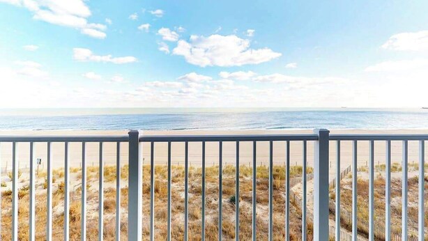 A beach view with a metal railing in the foreground. - Renovated, Oceanfront Condo w/ Gorgeous Ocean Views, Balcony, AC & WiFi (Ocean City)