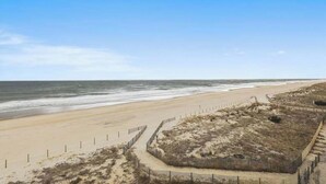 A beach with a sandy shore, a wooden fence, and a clear sky. - Renovated, Oceanfront Condo w/ Gorgeous Ocean Views, Balcony, AC & WiFi (Ocean City)